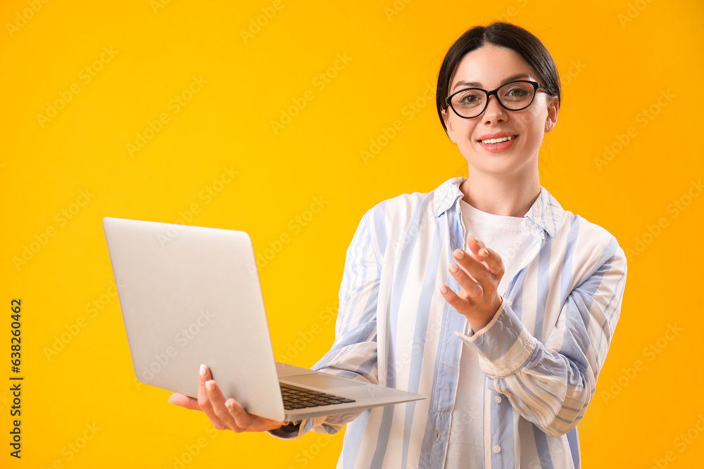 Female programmer with laptop on yellow background