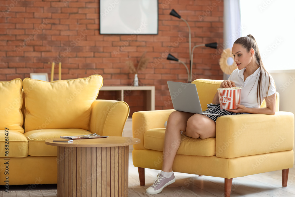 Young woman with popcorn watching movie on her day off at home