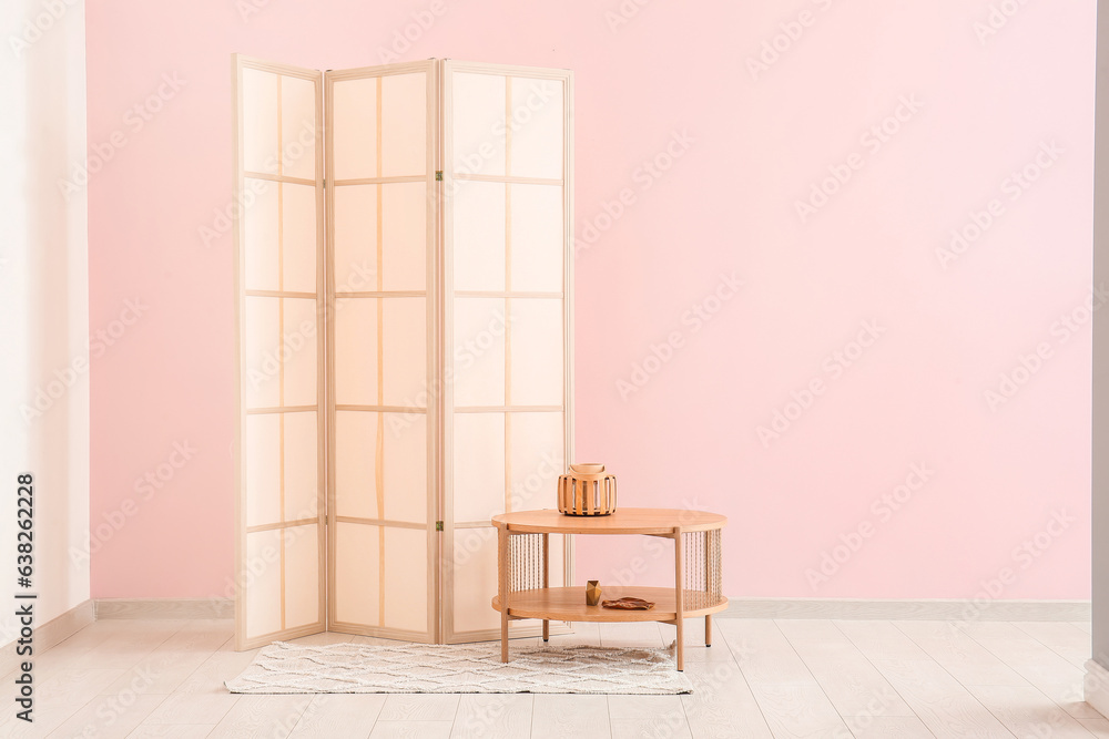 Folding screen and coffee table near pink wall