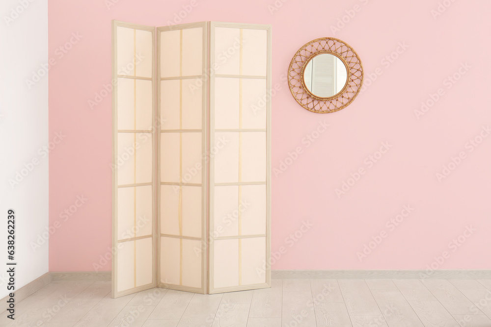 Folding screen and mirror near pink wall