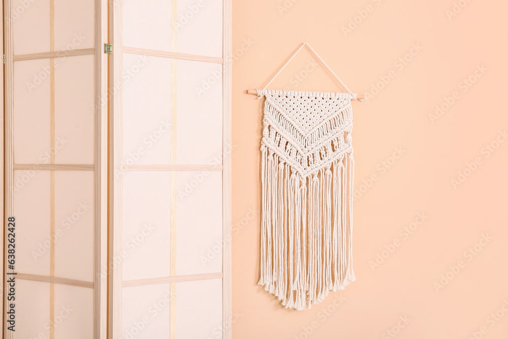 Folding screen and wicker decor near beige wall