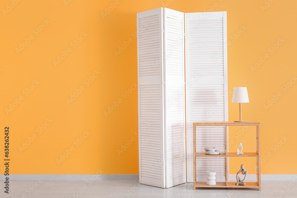 Folding screen and shelving unit near orange wall