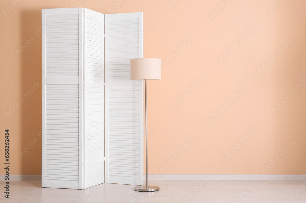 Folding screen and lamp near beige wall