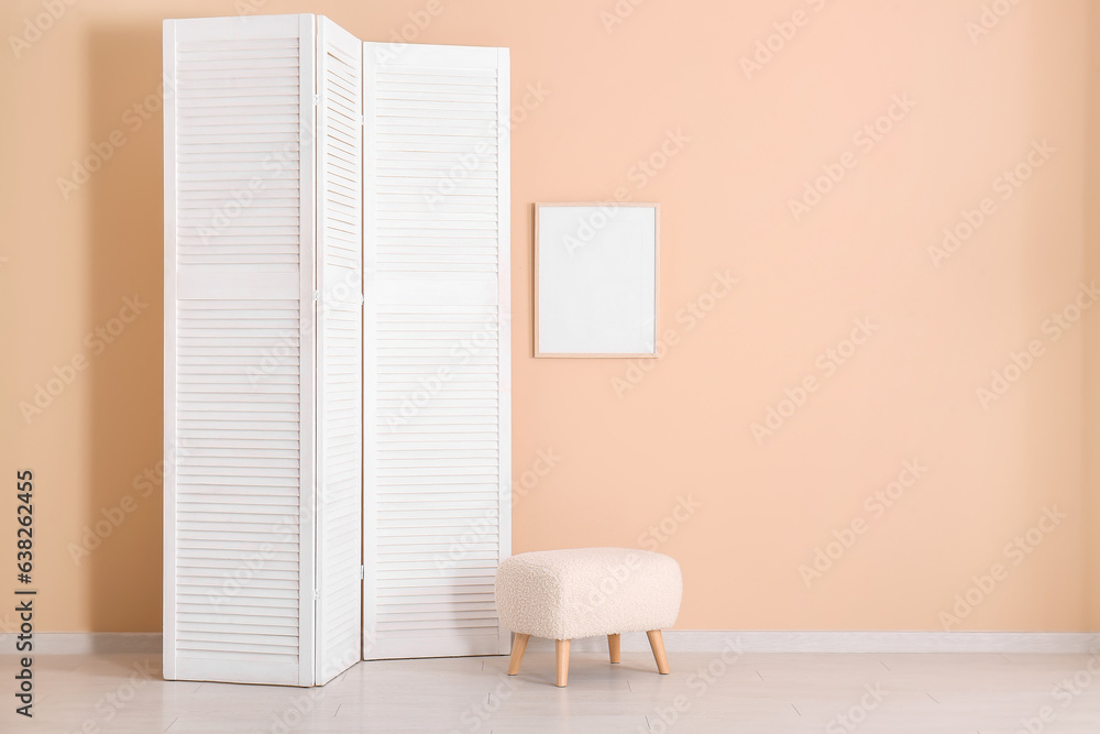 Folding screen and ottoman near beige wall