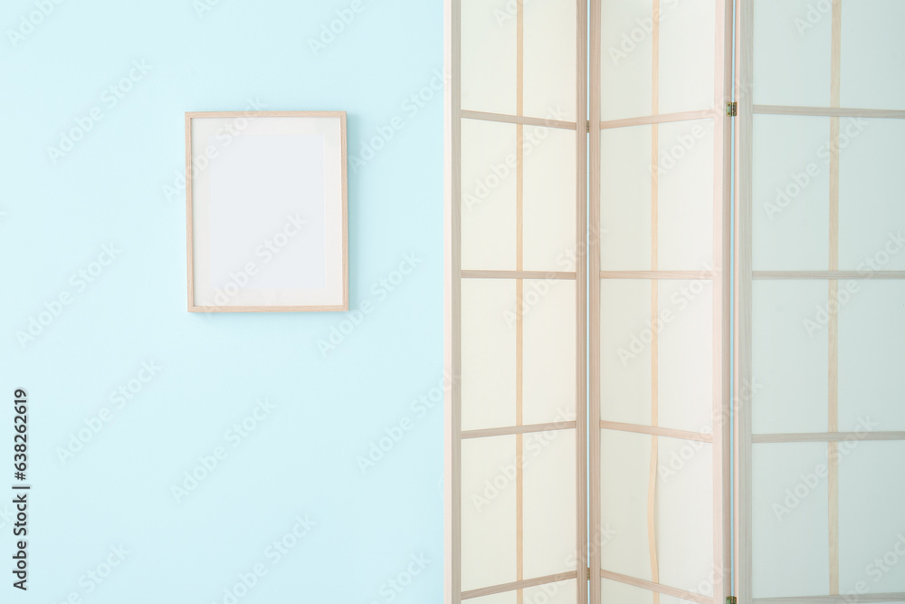 Folding screen and frame near blue wall