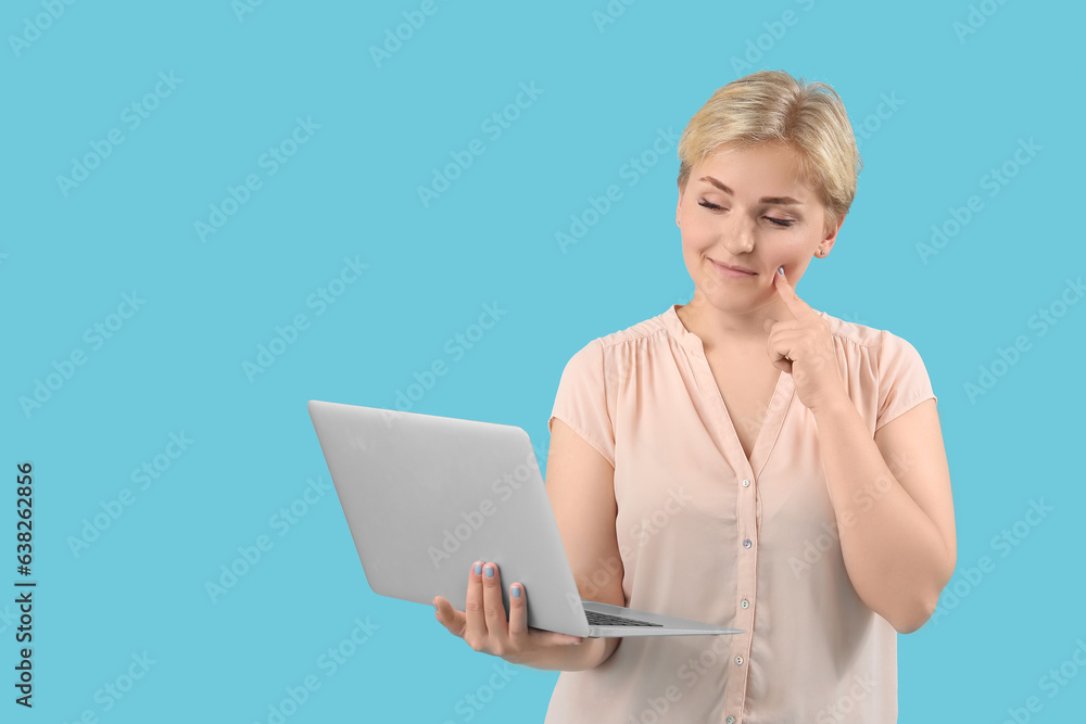 Thoughtful young female programmer with laptop on blue background