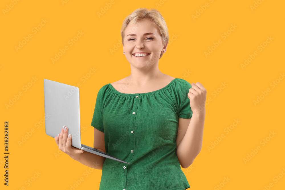 Happy young female programmer with laptop on yellow background