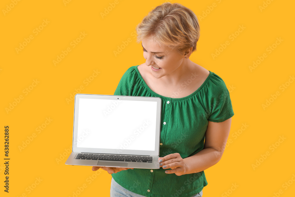 Happy young female programmer with laptop on yellow background