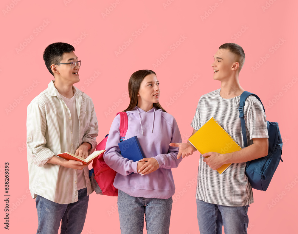 Happy students with backpacks and notebooks on pink background