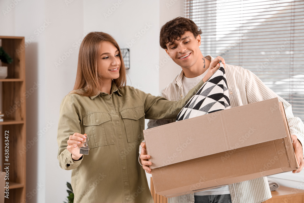 Young couple with keys and moving box in their new flat