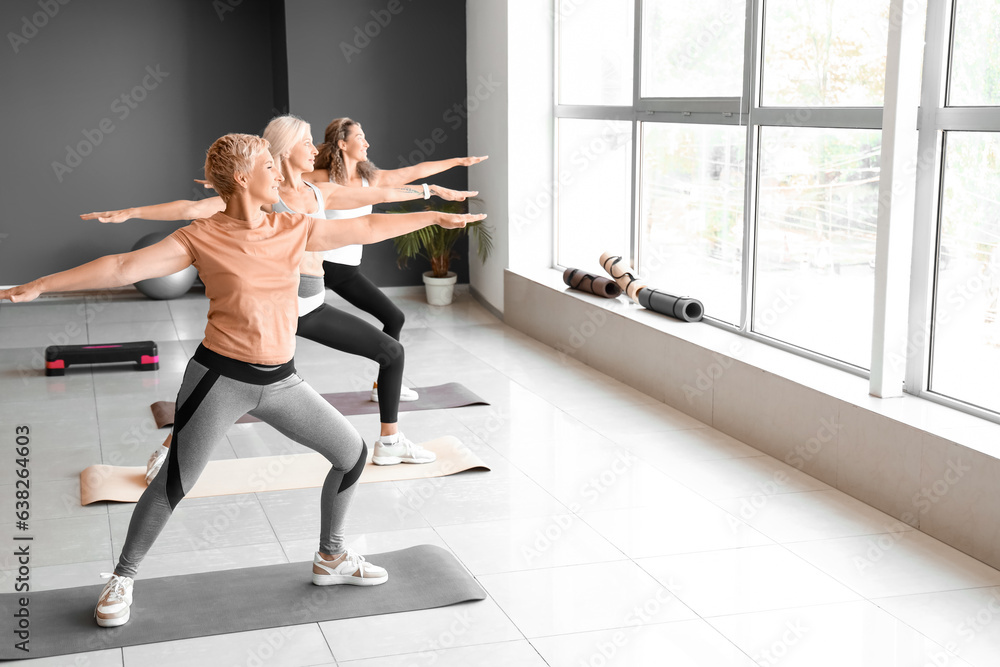 Sporty mature women practicing yoga in gym