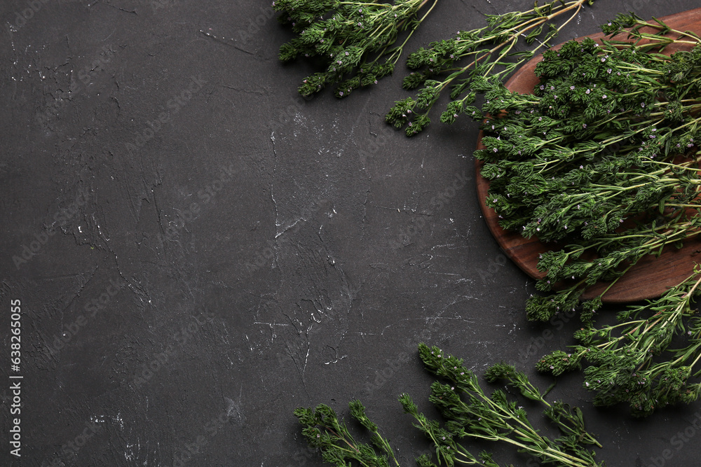 Wooden board with fresh thyme on dark background