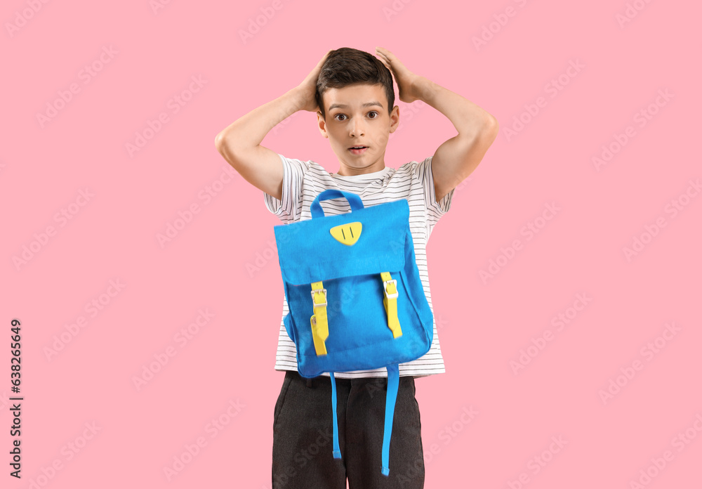 Portrait of shocked schoolboy with backpack on pink background