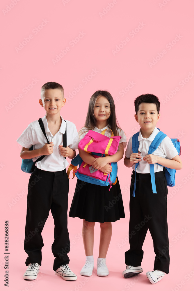 Little school children with backpacks on pink background