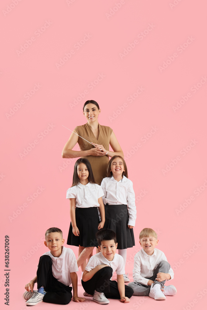 Little school children with female teacher on pink background