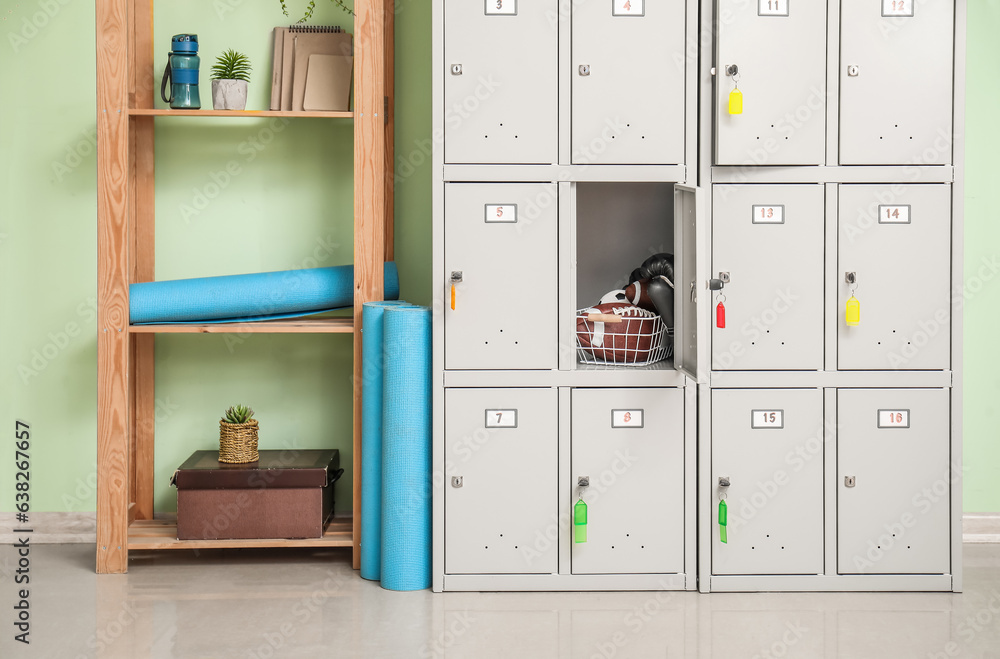 Modern locker and shelving unit with sports equipment near green wall