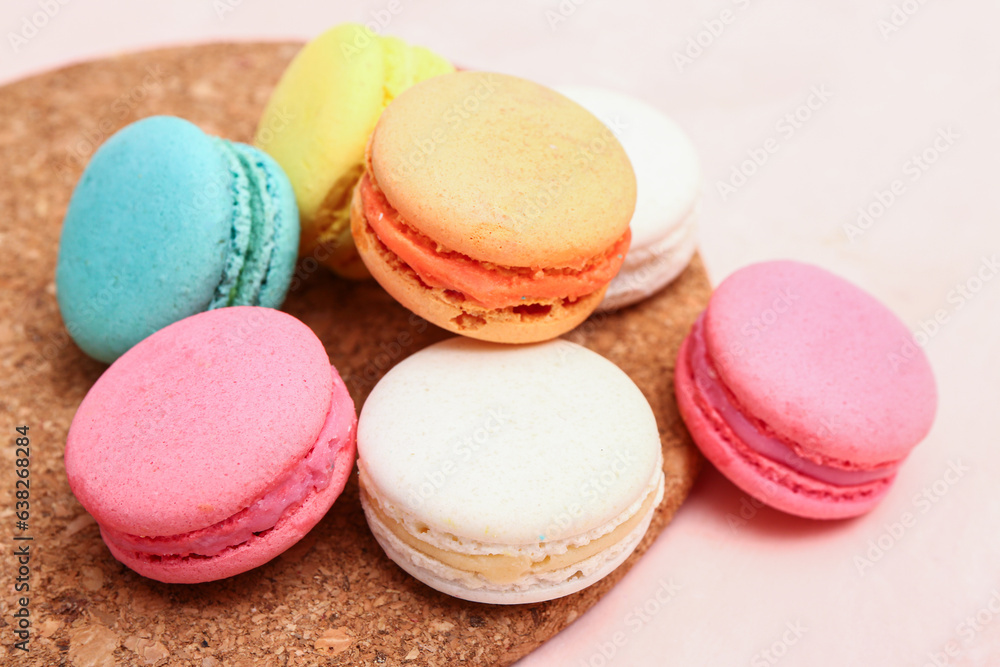 Board with sweet macaroons on pink background