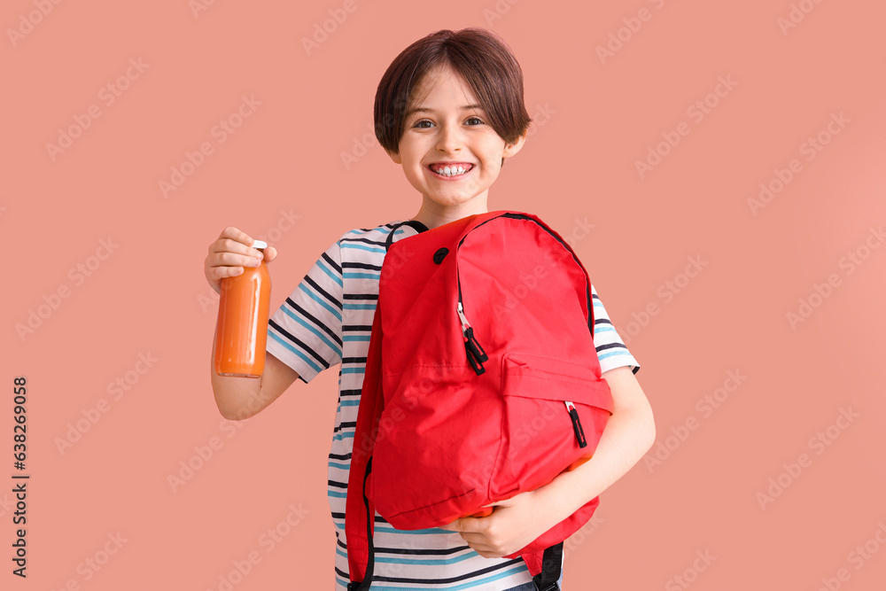 Happy little boy with backpack and bottle of juice on color background