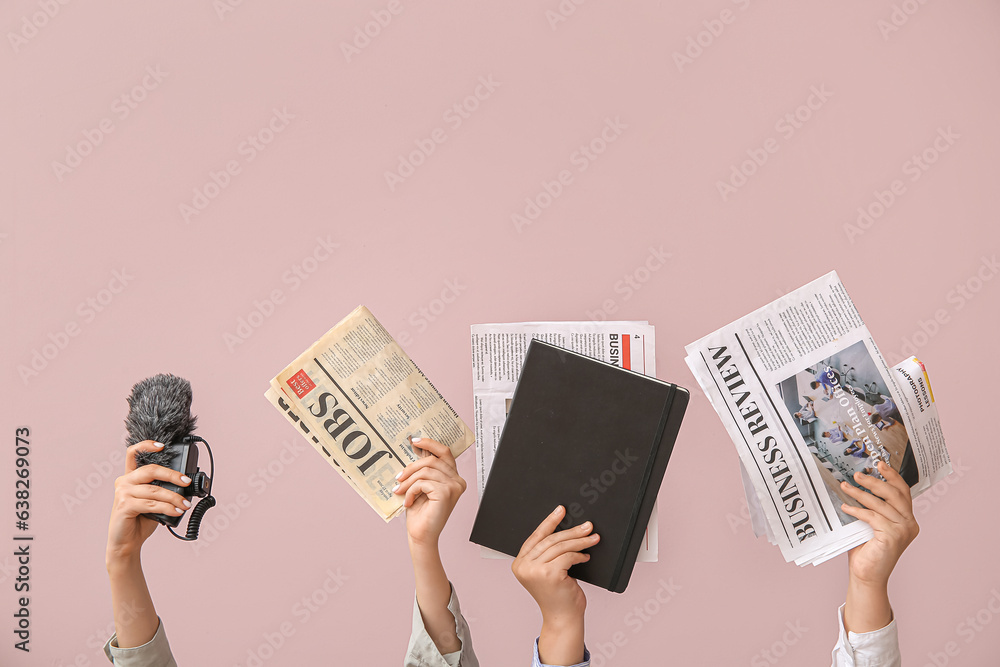 Female hands with different newspapers, notebook and microphone on color background