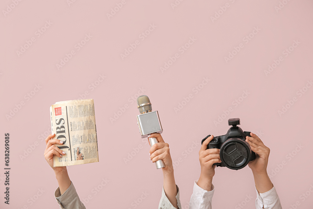 Female hands with newspaper, microphone and photo camera on color background