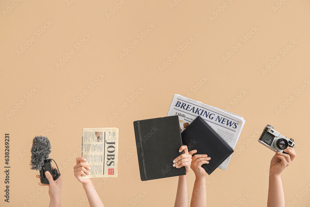 Female hands with notebooks, newspapers, microphone and photo camera on color background