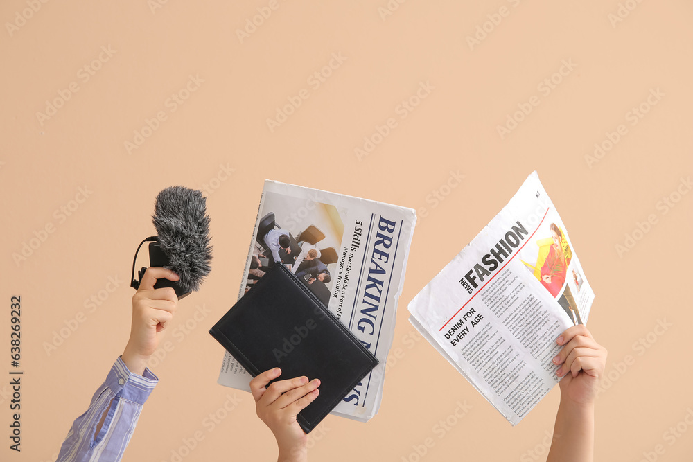 Female hands with microphone, notebook and newspapers on color background