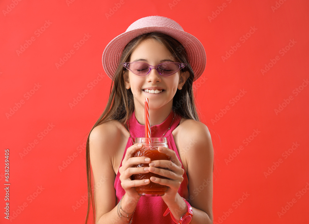 Little girl with glass of juice on red background