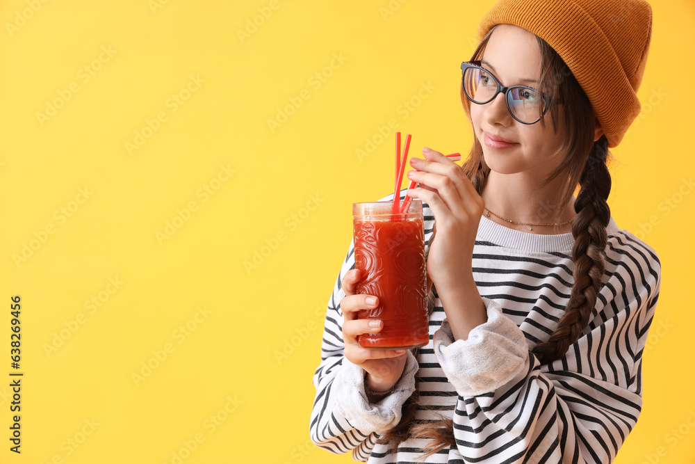 Little girl with glass of red juice on yellow background, closeup