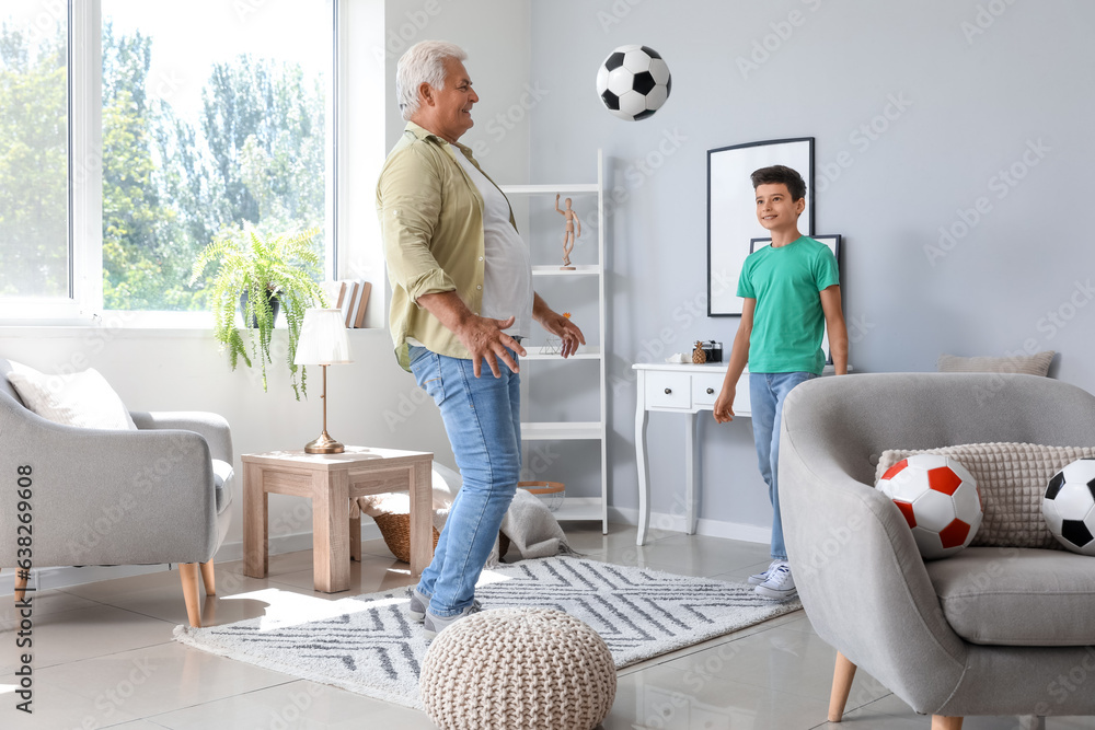 Little boy with his grandfather playing football at home