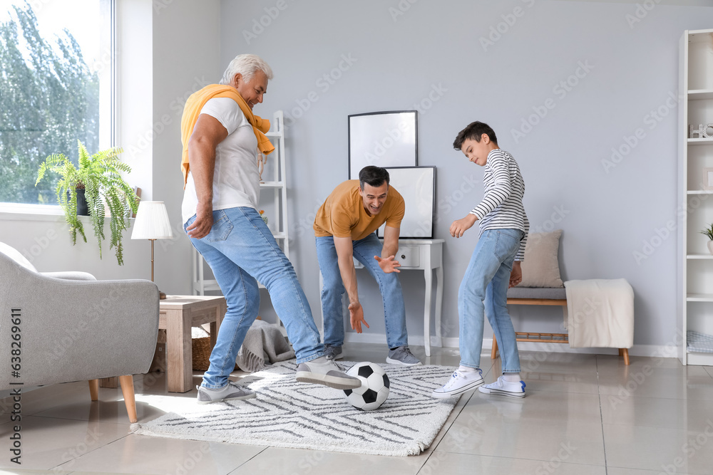 Little boy with his dad and grandfather playing football at home