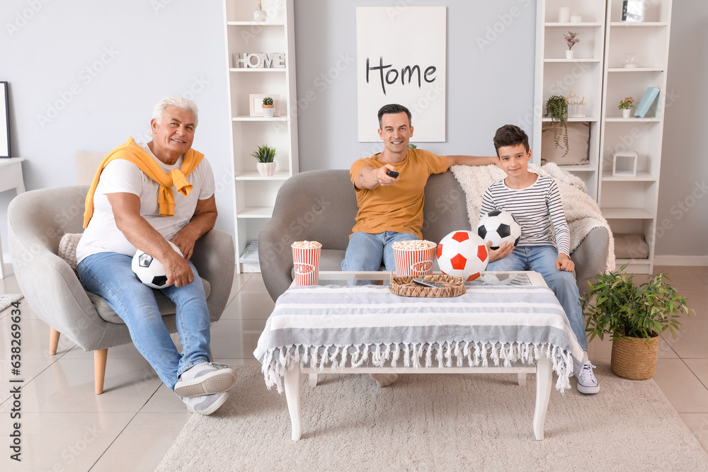 Little boy with his dad and grandfather watching football game at home