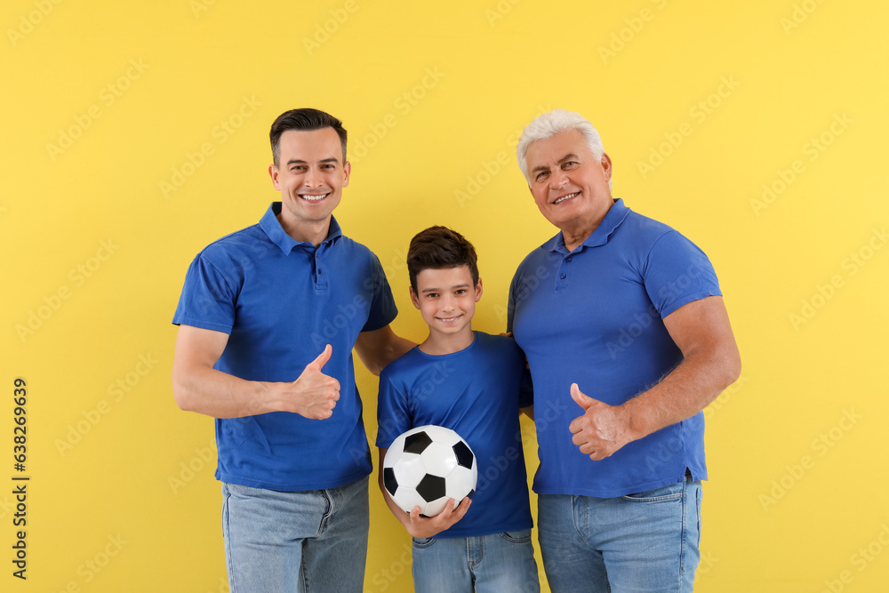 Little boy with his dad and grandfather holding soccer ball on yellow background