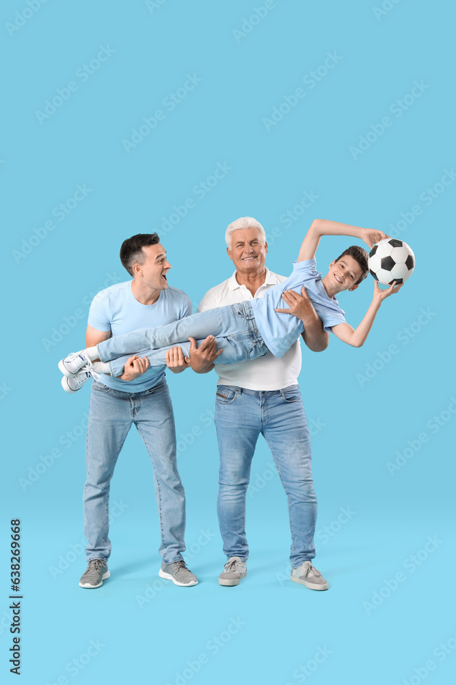 Little boy with his dad and grandfather holding soccer ball on blue background