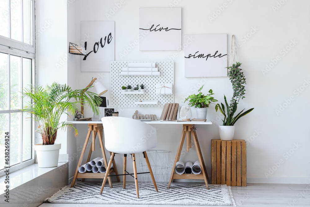 Interior of light office with workplace, pegboard and houseplants