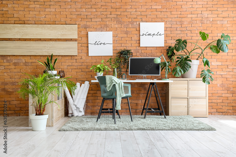 Interior of stylish office with modern workplace, shelving unit and houseplants