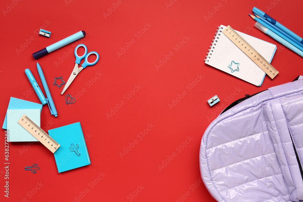 Stylish school backpack with different stationery supplies on red background