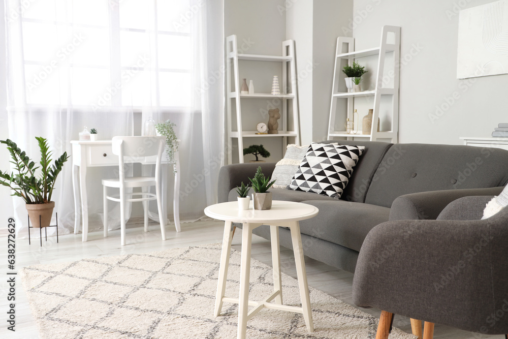 Interior of light living room with cozy armchair and grey sofa