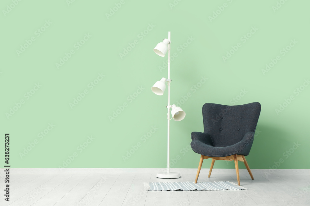 Comfortable armchair and floor lamp near color wall