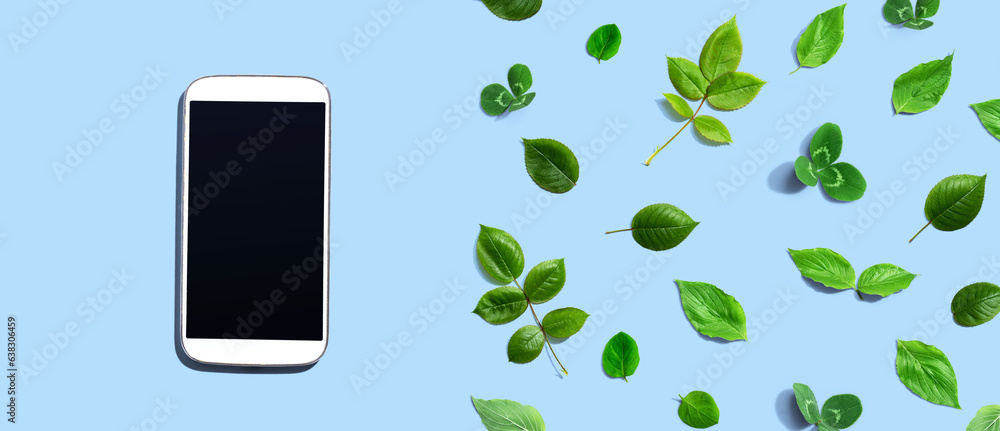 White smartphone with green leaves - flat lay