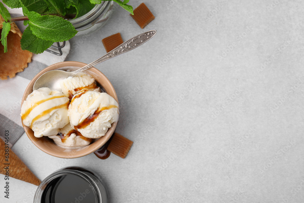 Scoops of ice cream with caramel sauce and candies on light grey table, flat lay. Space for text