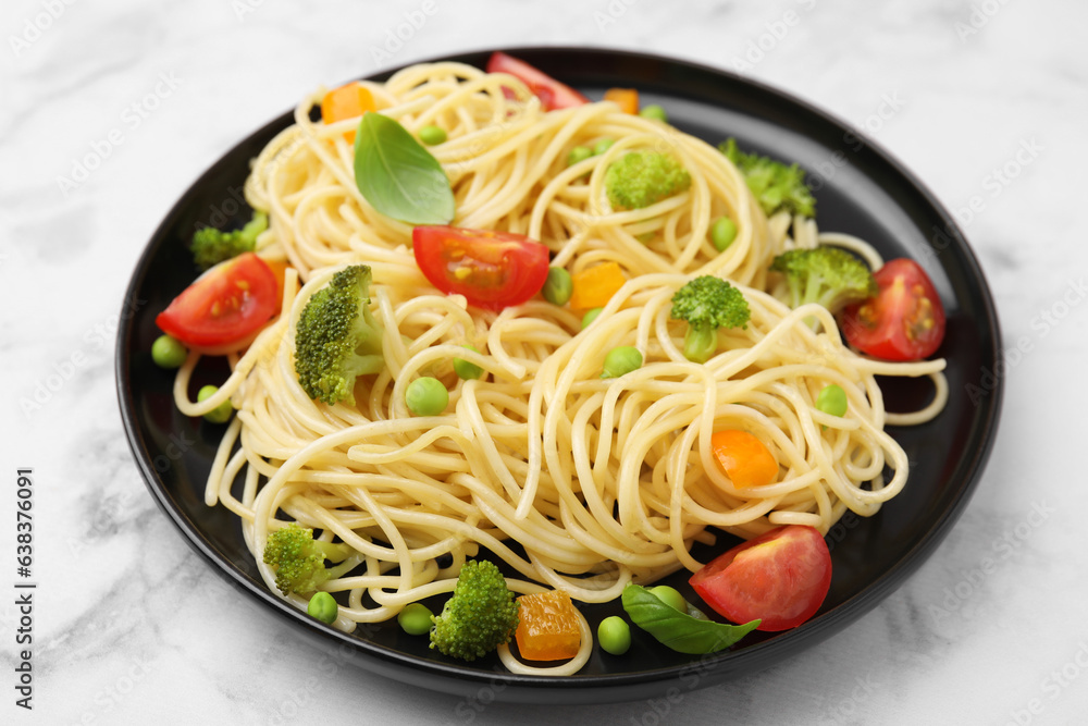 Plate of delicious pasta primavera on white marble table, closeup