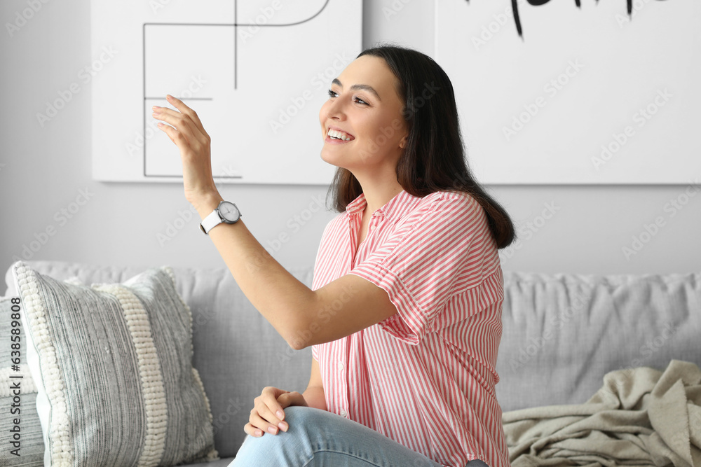 Young woman with stylish wristwatch sitting on sofa at home