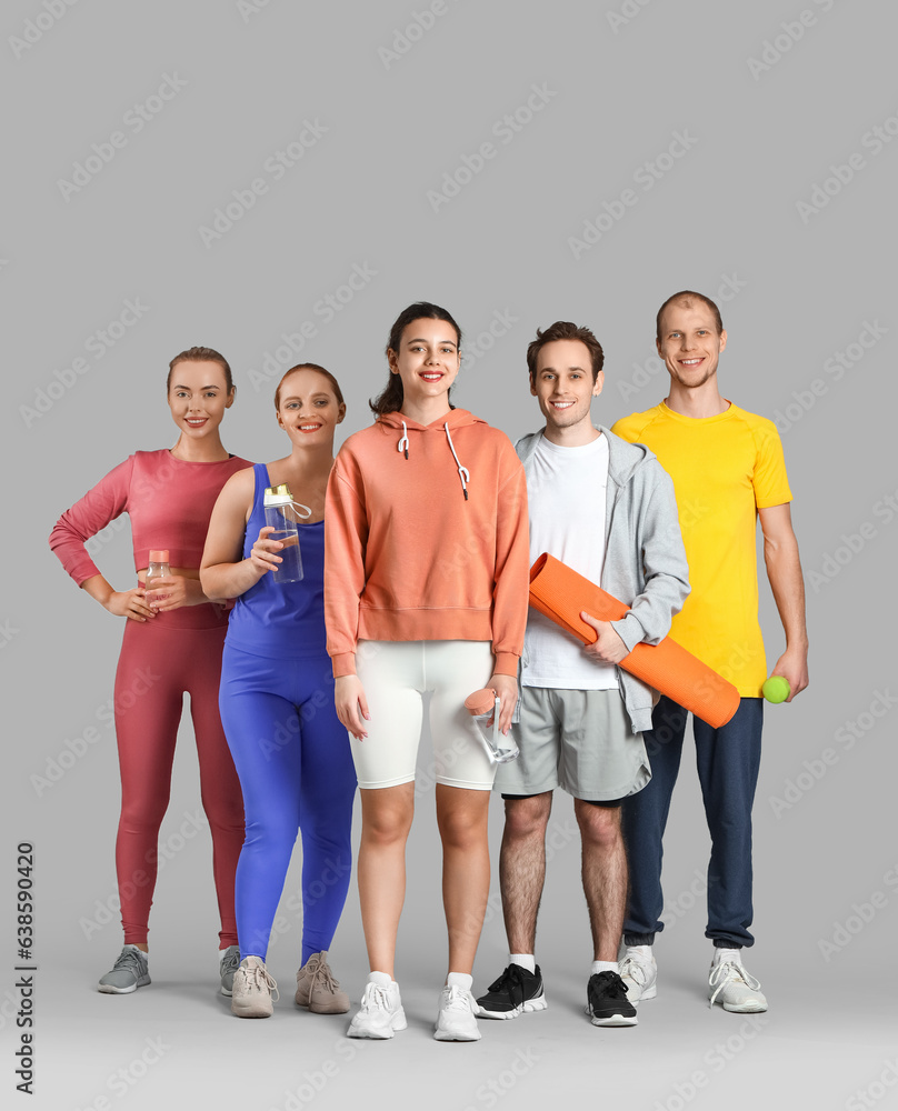 Group of sporty young people with equipment on grey background