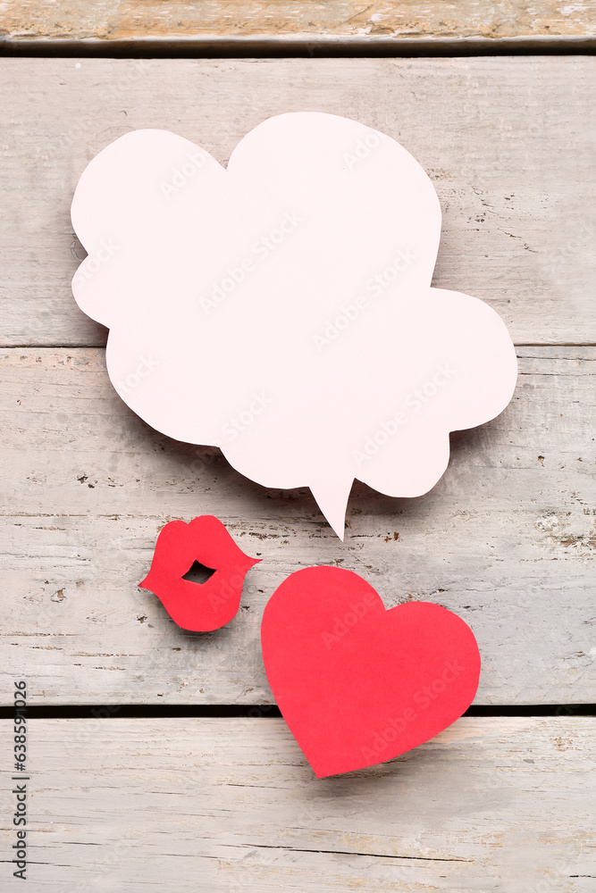 Paper lips and heart with blank speech bubble on grey wooden background