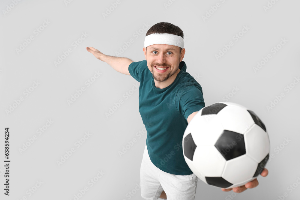 Happy man with soccer ball on light background