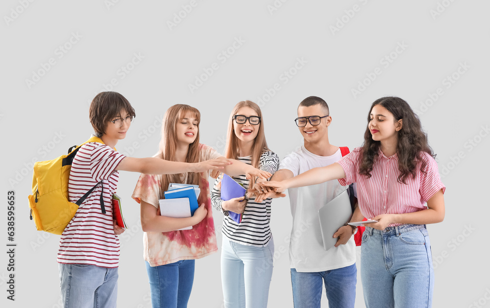 Group of students putting hands together on light background