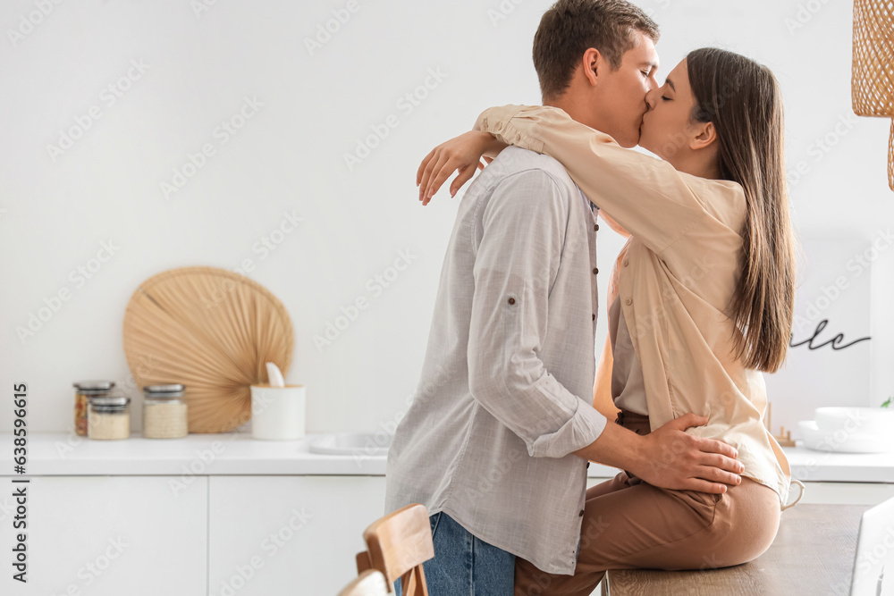 Happy young couple kissing in kitchen