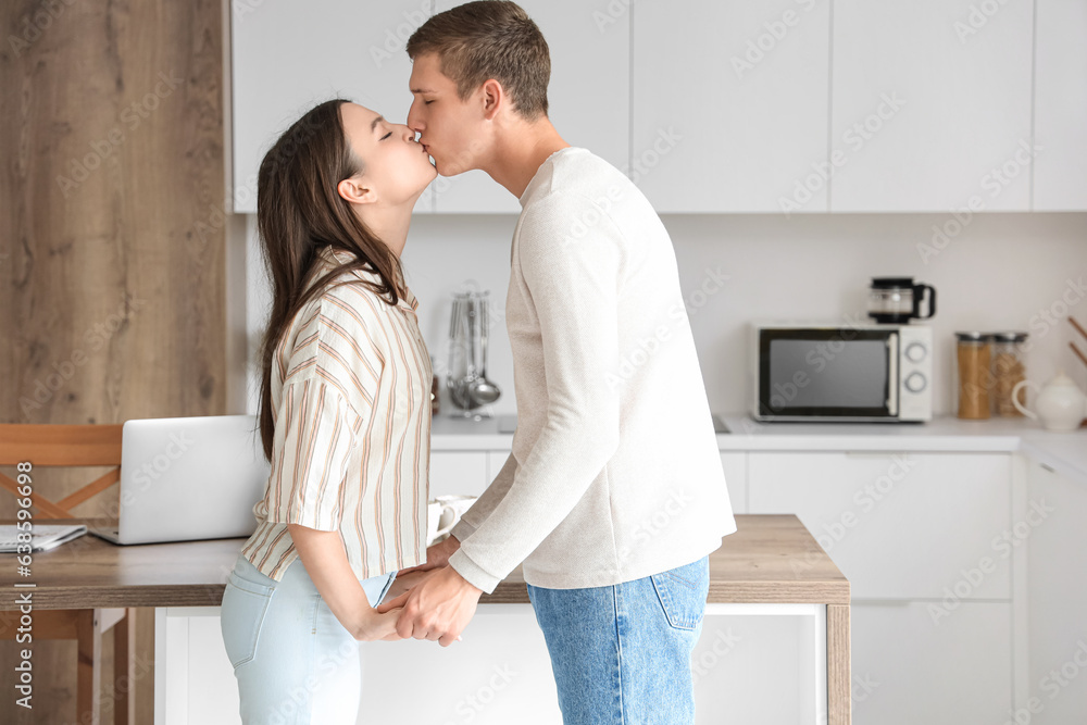 Happy young couple kissing in kitchen