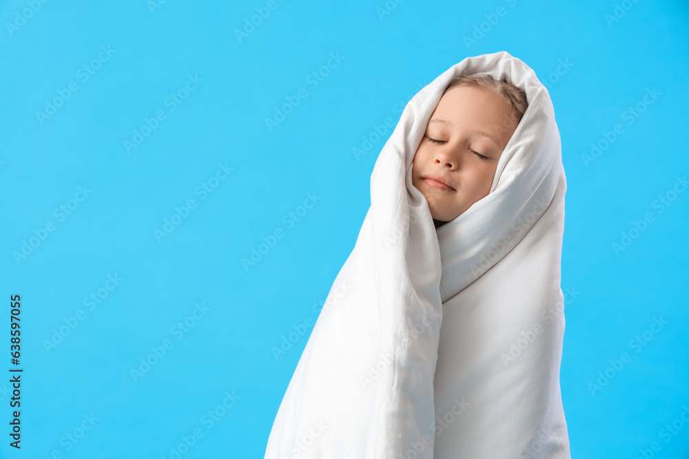 Little girl wrapped in blanket on blue background