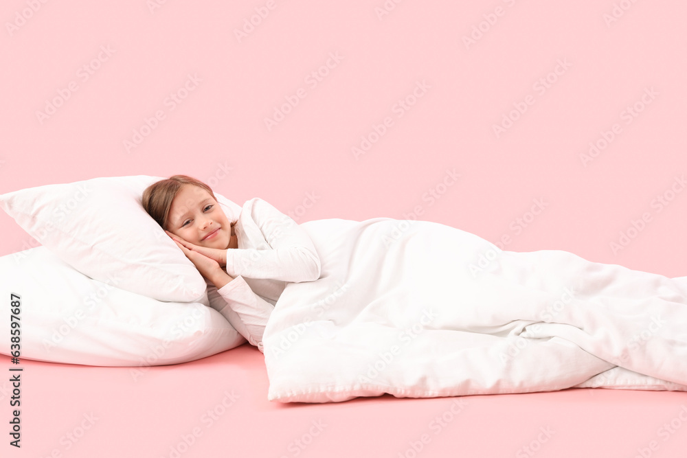 Little girl with pillow and blanket on pink background